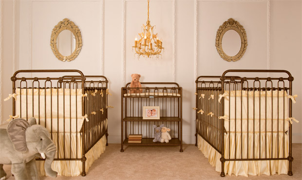 Paired gold iron cribs dressed in warm yellow makes this upscale twin nursery stylish and graceful.